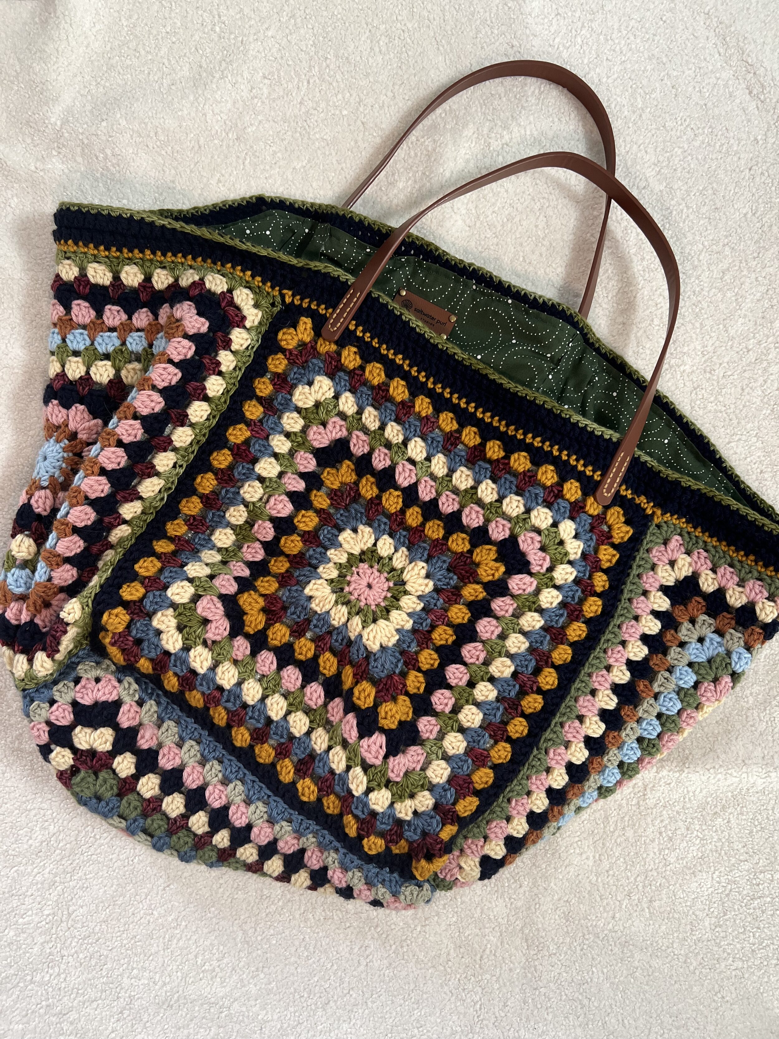 Saltwater Purl's colorful granny square tote with leather handles and green fabric lining
